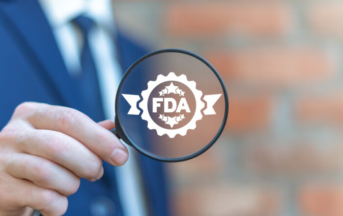 FDA in magnifying glass held by quality and compliance management professional